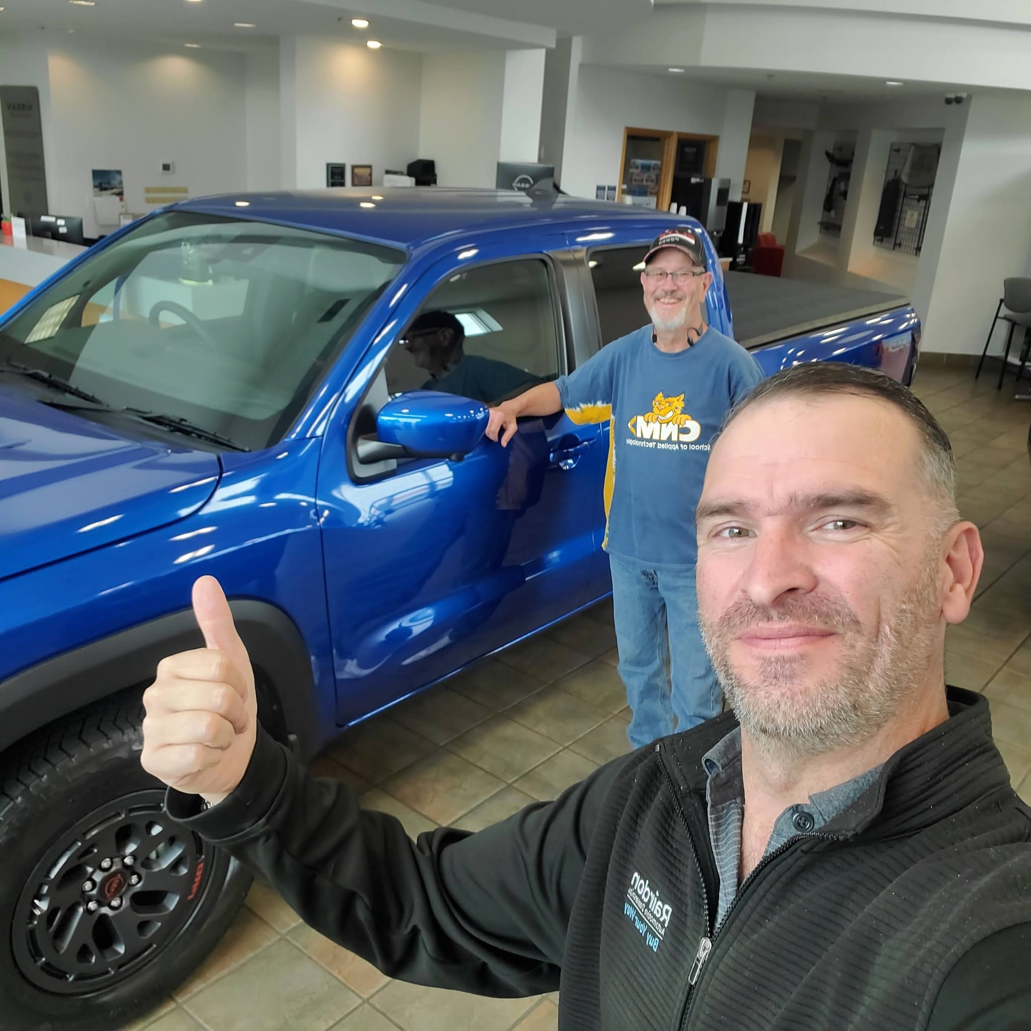 Happy customer with Ian next to a blue truck — another successful vehicle delivery